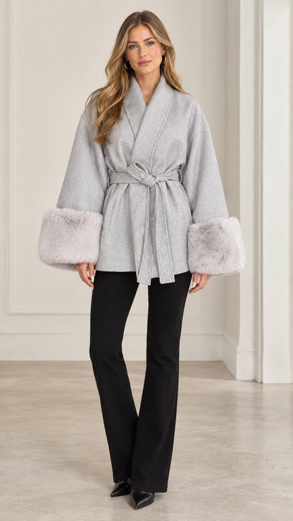 Front view of model wearing grey wrap coat with faux fur cuffs and black flared pants
