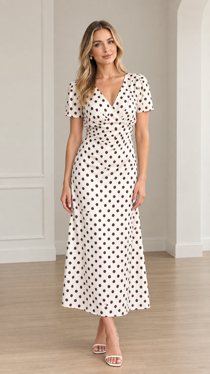 Front view of woman wearing white and brown polka dot short sleeve midi dress