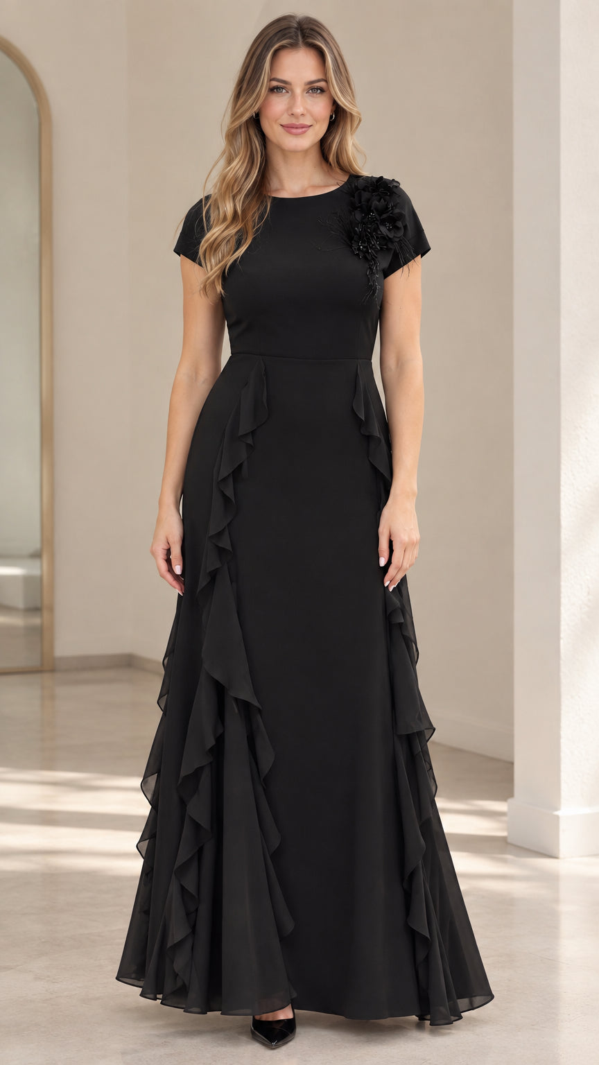 Front view of black short sleeve maxi evening dress with floral shoulder appliqué and cascading side ruffles