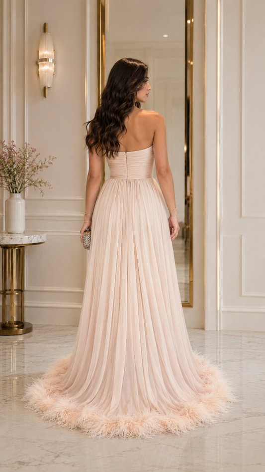 Back view of blush strapless pleated evening gown with feather-trimmed hem