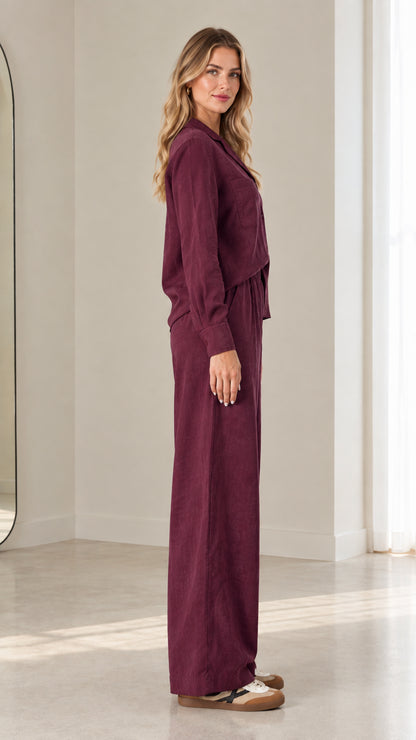 Side profile of model in relaxed-fit burgundy matching long-sleeve shirt and trouser set