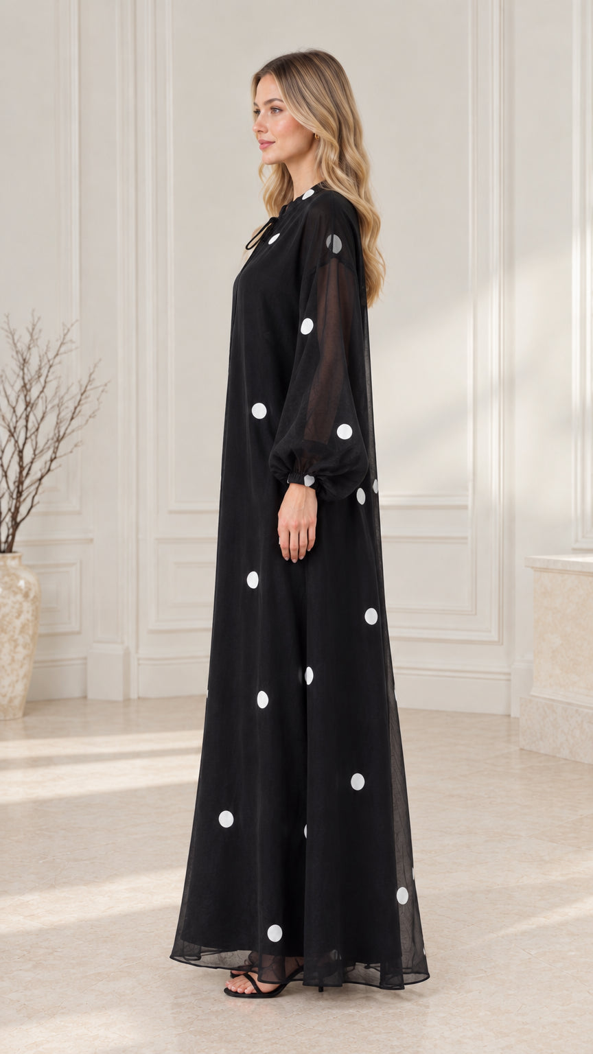 Side profile view of black long sleeve polka dot modest dress