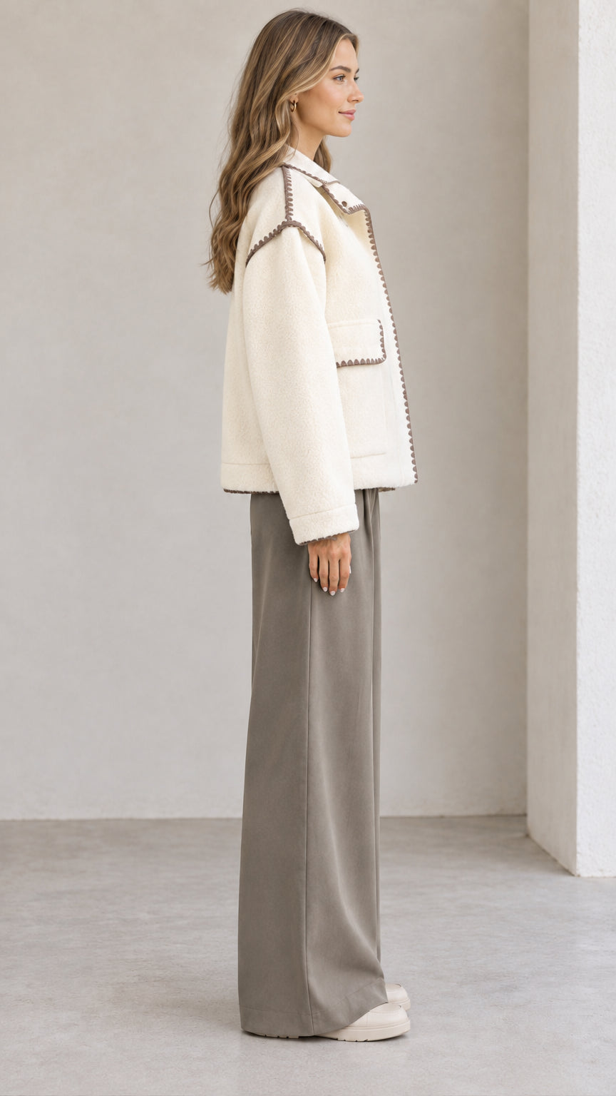 Side view of model wearing cream collared fleece jacket with contrast stitch