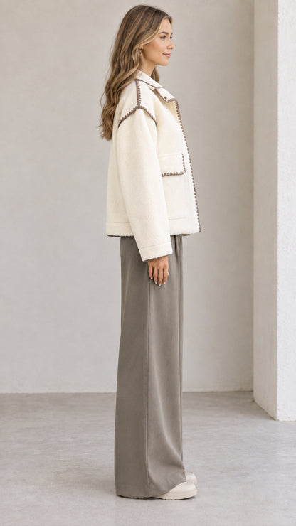 Side view of model wearing cream collared fleece jacket with contrast stitch