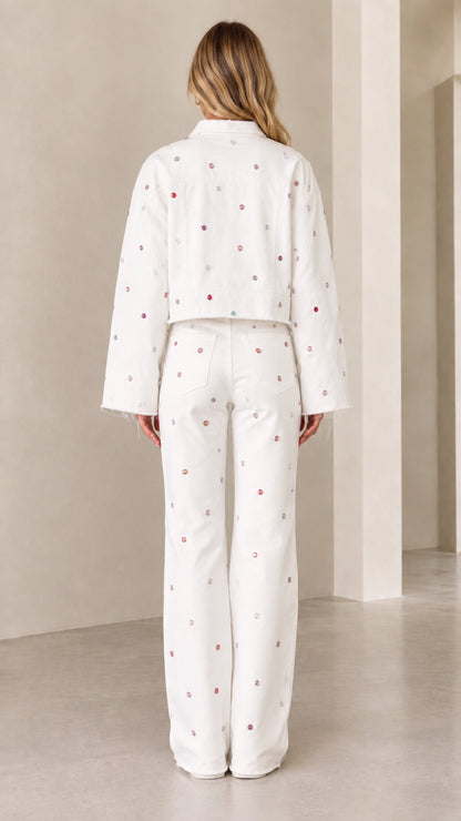 Back view of woman wearing white embellished cropped jacket and wide-leg trousers