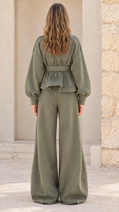 Back view of woman wearing olive green belted jacket and wide leg trousers