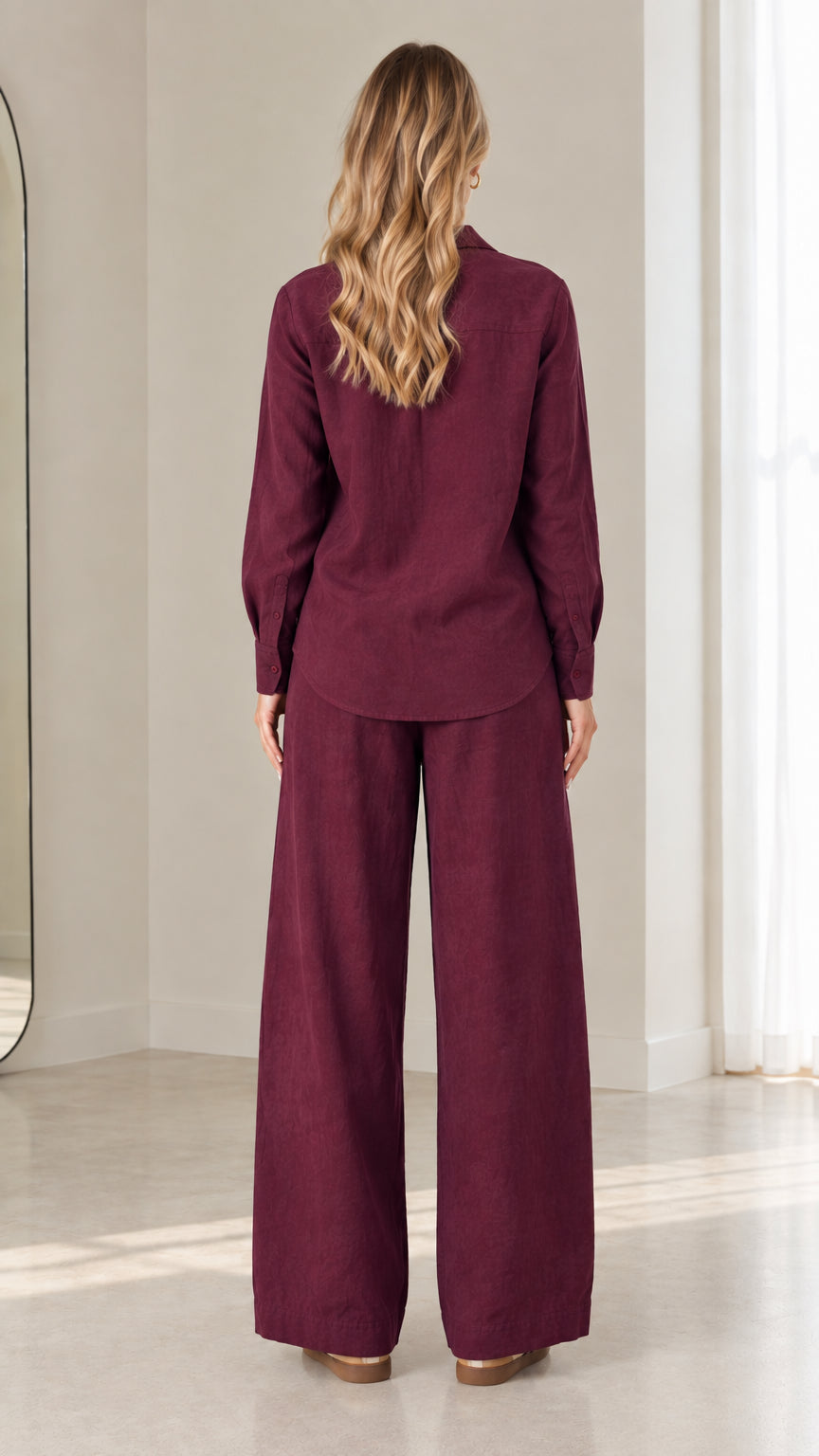 Back view of model showing the clean drape of the burgundy button-down shirt and wide-leg pants