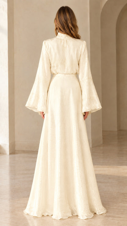 Back view of woman wearing ivory long sleeve maxi dress showing fitted back and flared skirt