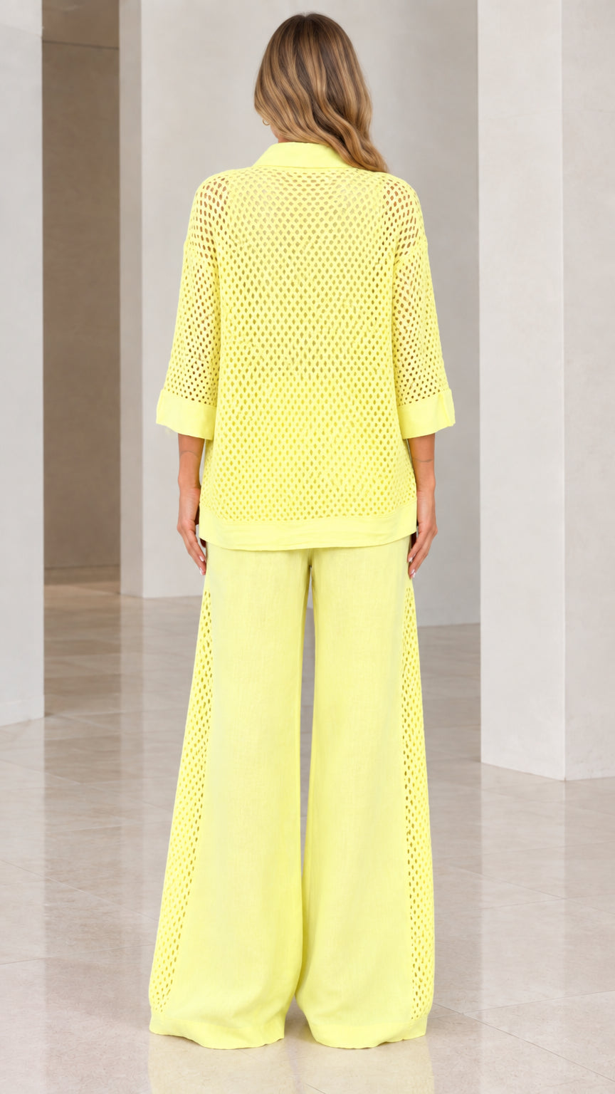 Back view of woman wearing light yellow open knit shirt and wide-leg pants set