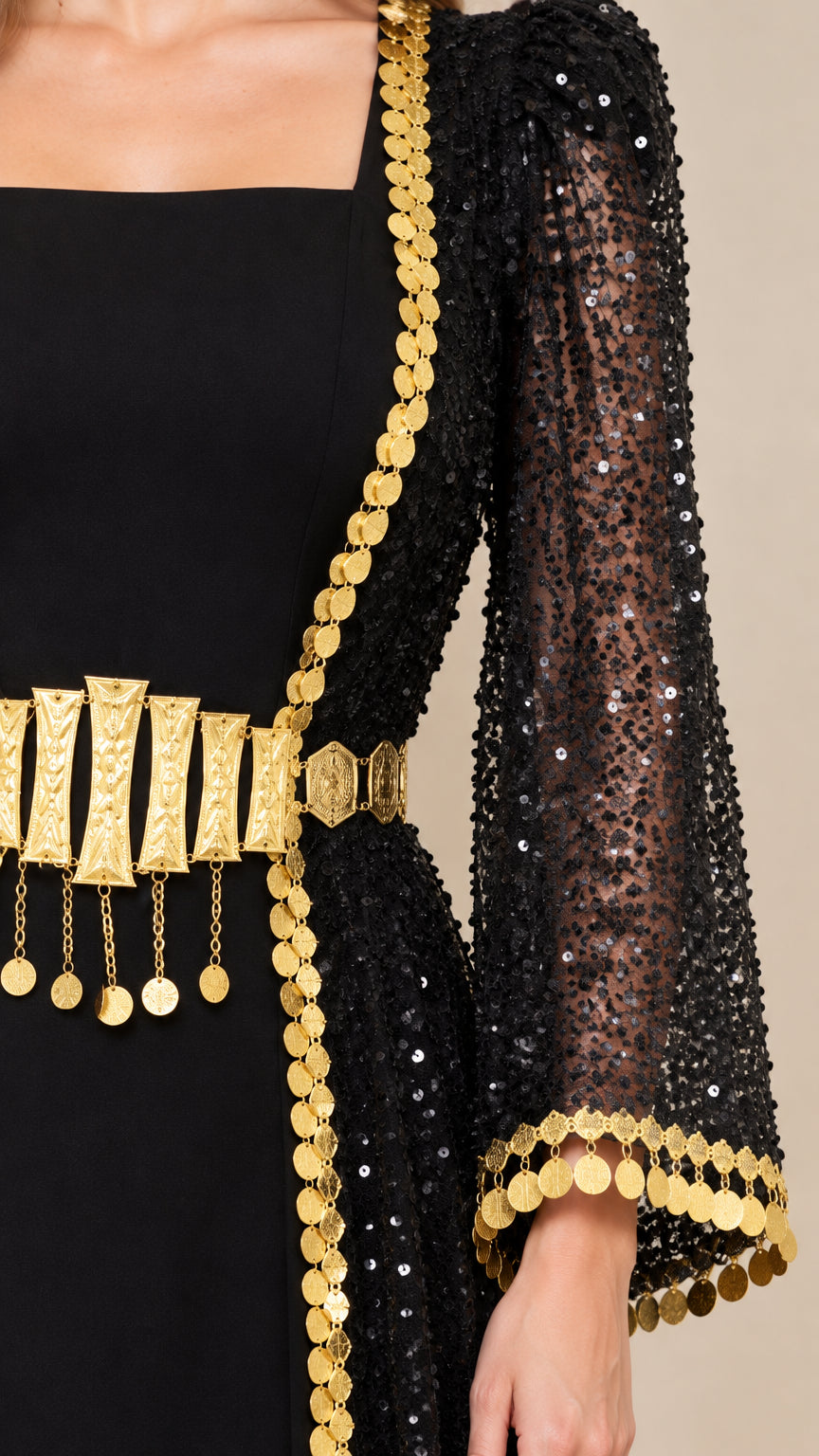 Close-up detail of black sequin mesh, gold coin trim, and dangling metallic waist ornament