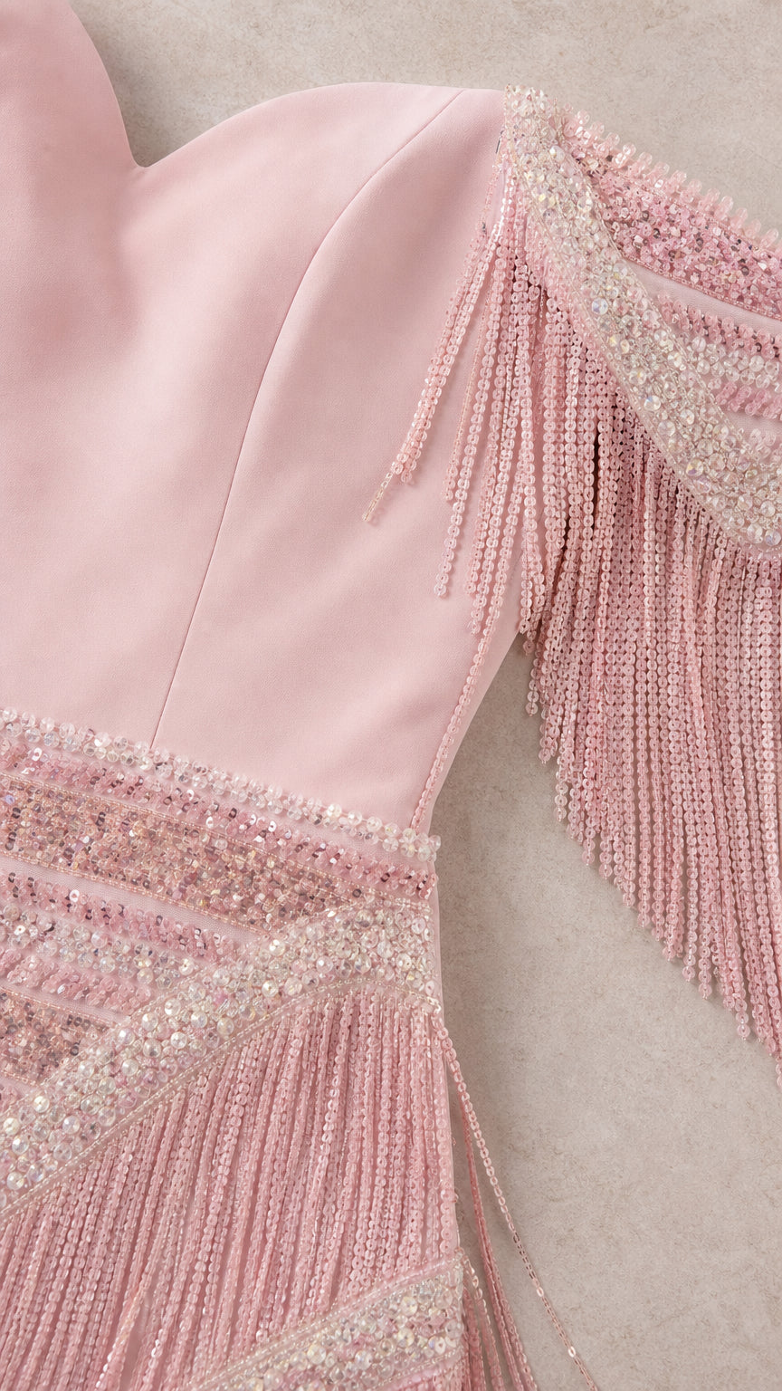 Close-up detail of dusty rose sweetheart neckline, beadwork, and tassel fringe sleeve