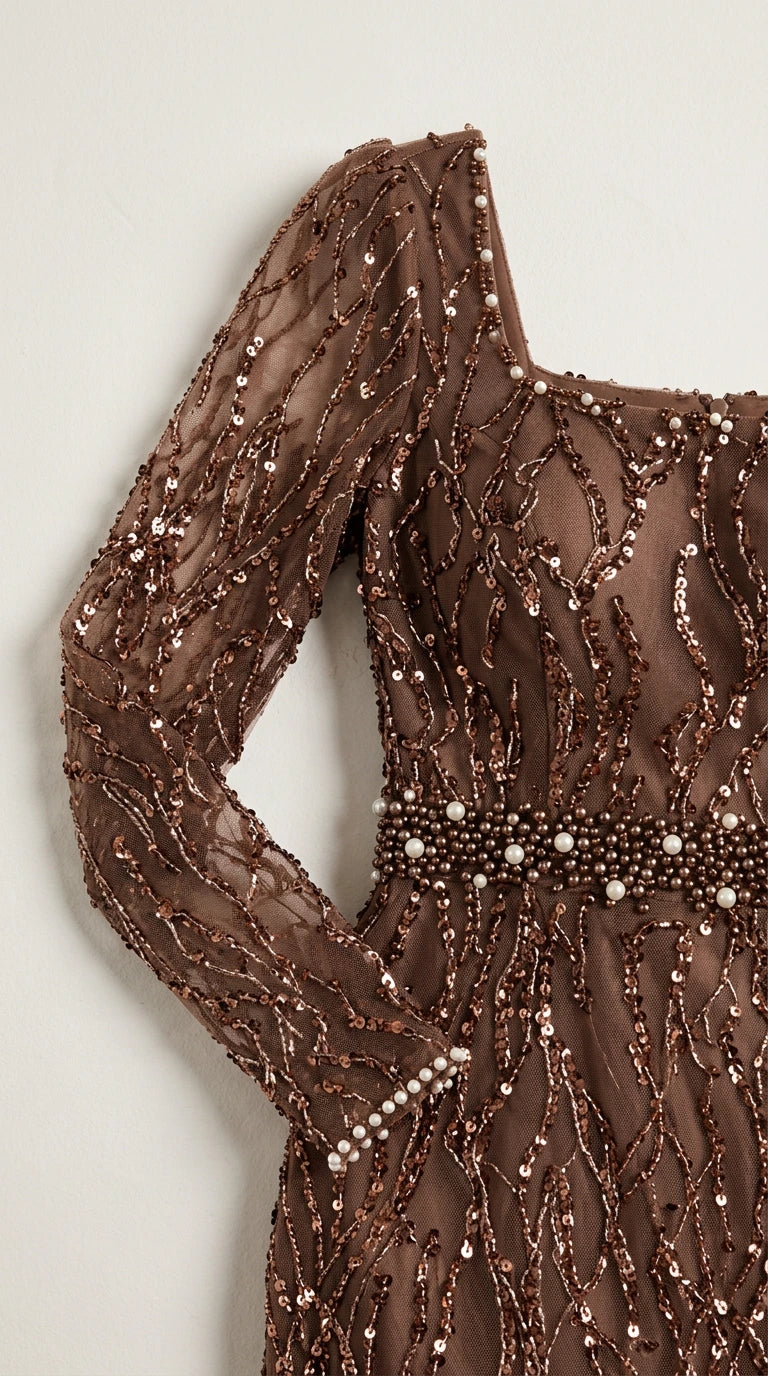 Close-up detail of sheer sequined sleeve and beaded waistband on brown dress