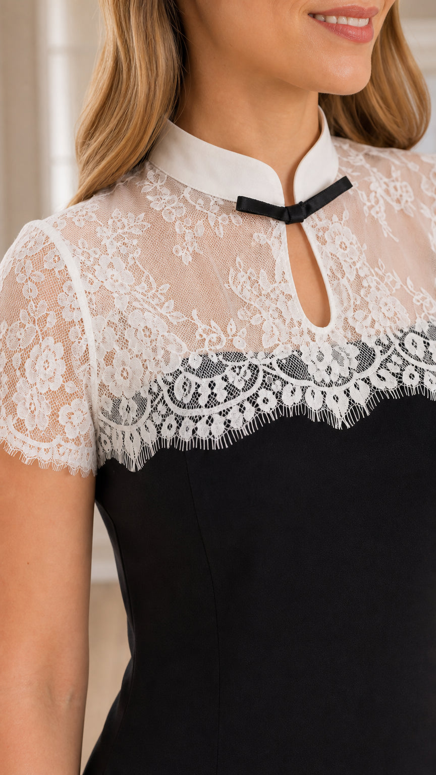 Close-up of white floral lace bodice, stand collar, and bow keyhole detail on black dress