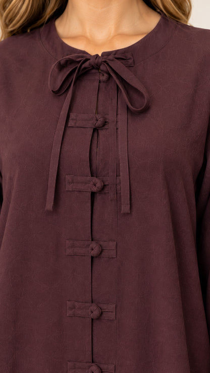 Close up of neckline tie and fabric knot frog buttons on burgundy dress