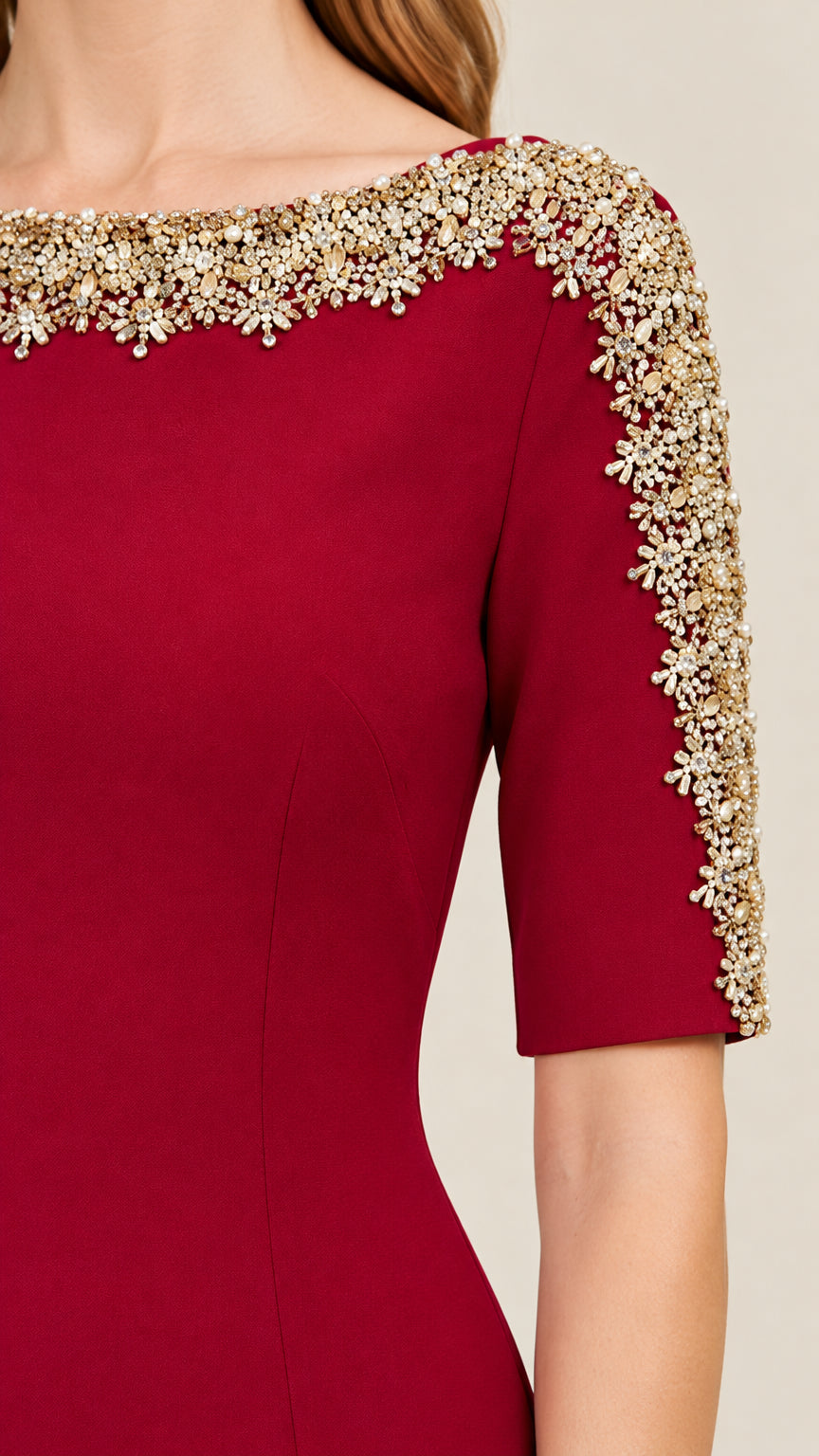 Close-up detail of ornate gold and crystal beadwork on burgundy gown neckline and sleeve
