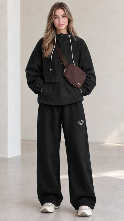 Full-length front view of model wearing black half-zip hooded anorak jacket