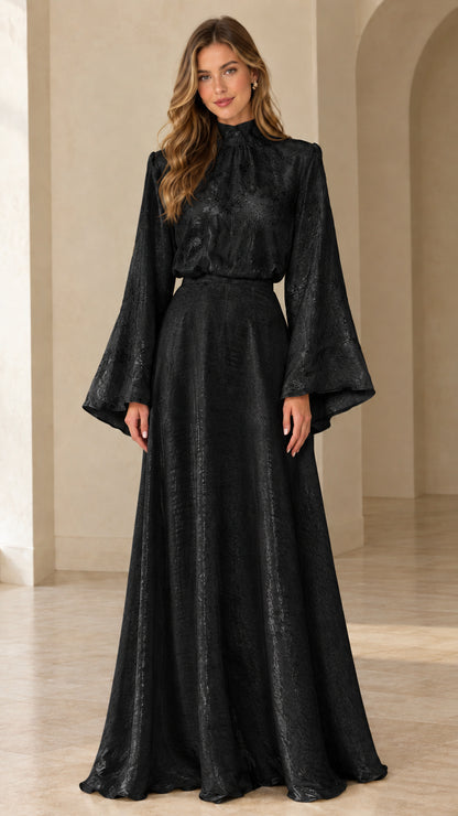 Front full view of woman wearing black high neck bell sleeve jacquard maxi gown