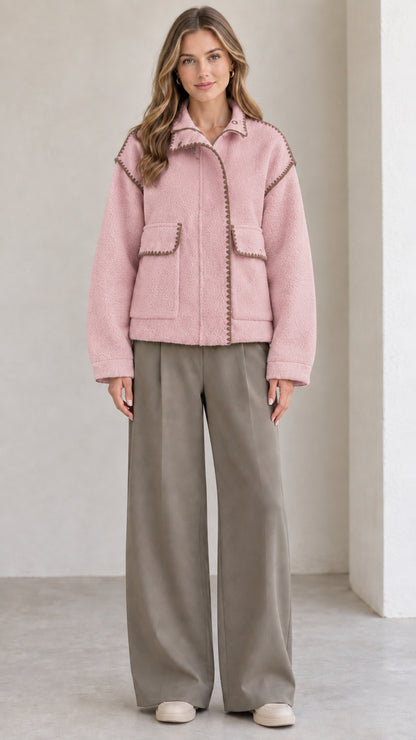 Model wearing dusty pink fleece jacket with brown contrast blanket stitching