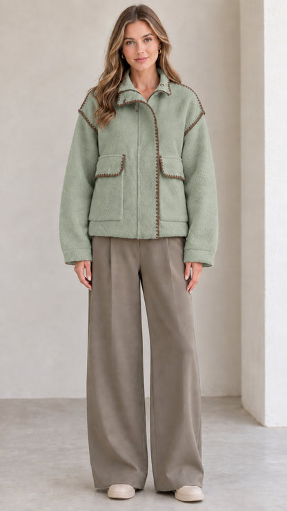 Model wearing sage green fleece jacket with brown contrast trim