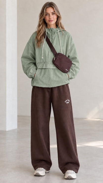 Full-length front view of model wearing sage green half-zip hooded anorak jacket