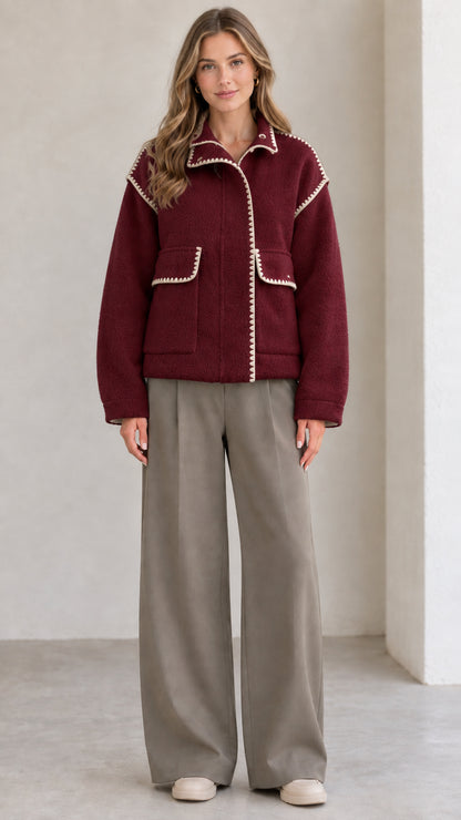 Model wearing burgundy red fleece jacket with white contrast blanket stitching