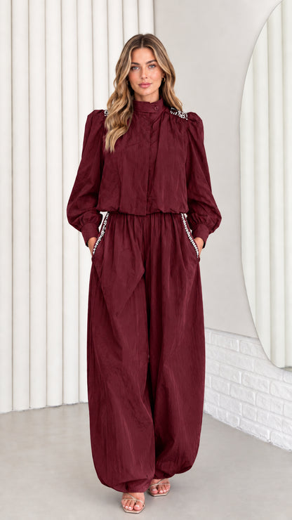 Front view of model wearing burgundy wine-colored rhinestone jumpsuit